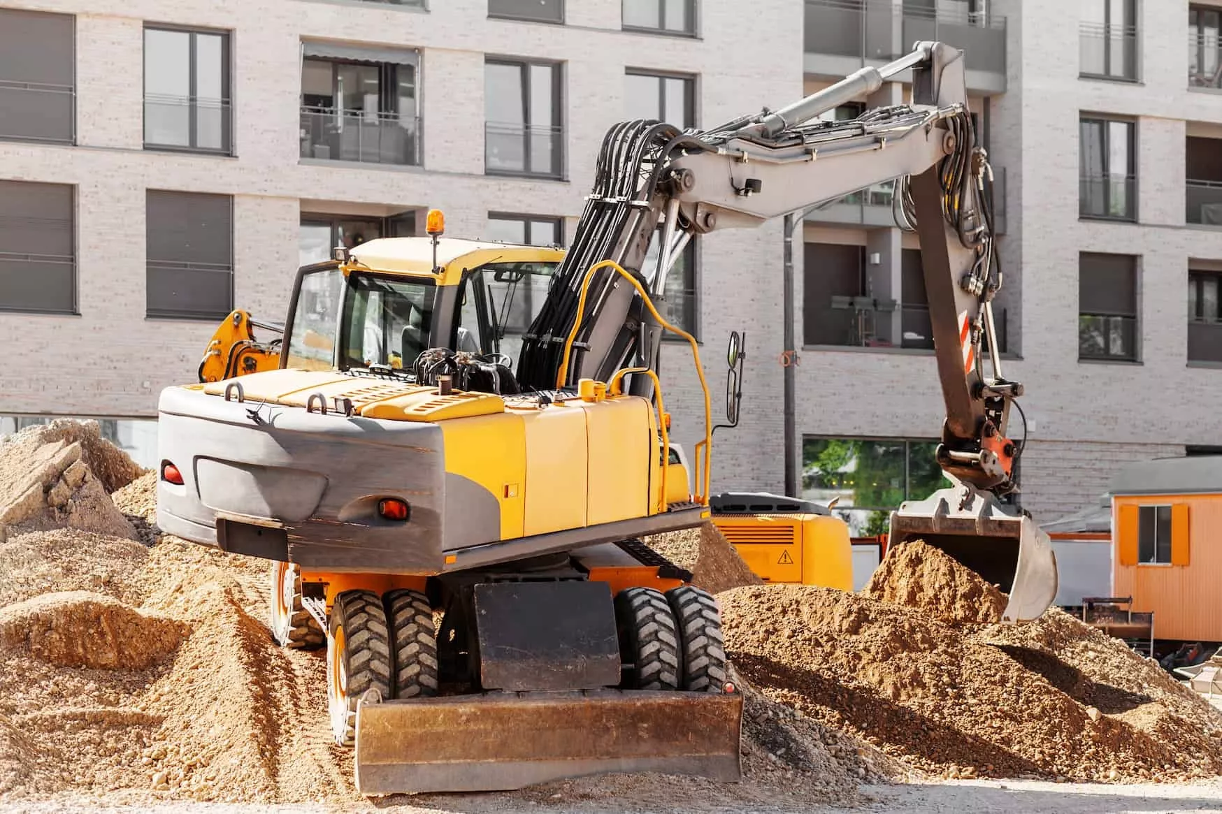 Wheeled excavator performing earthmoving operations at an urban construction site
