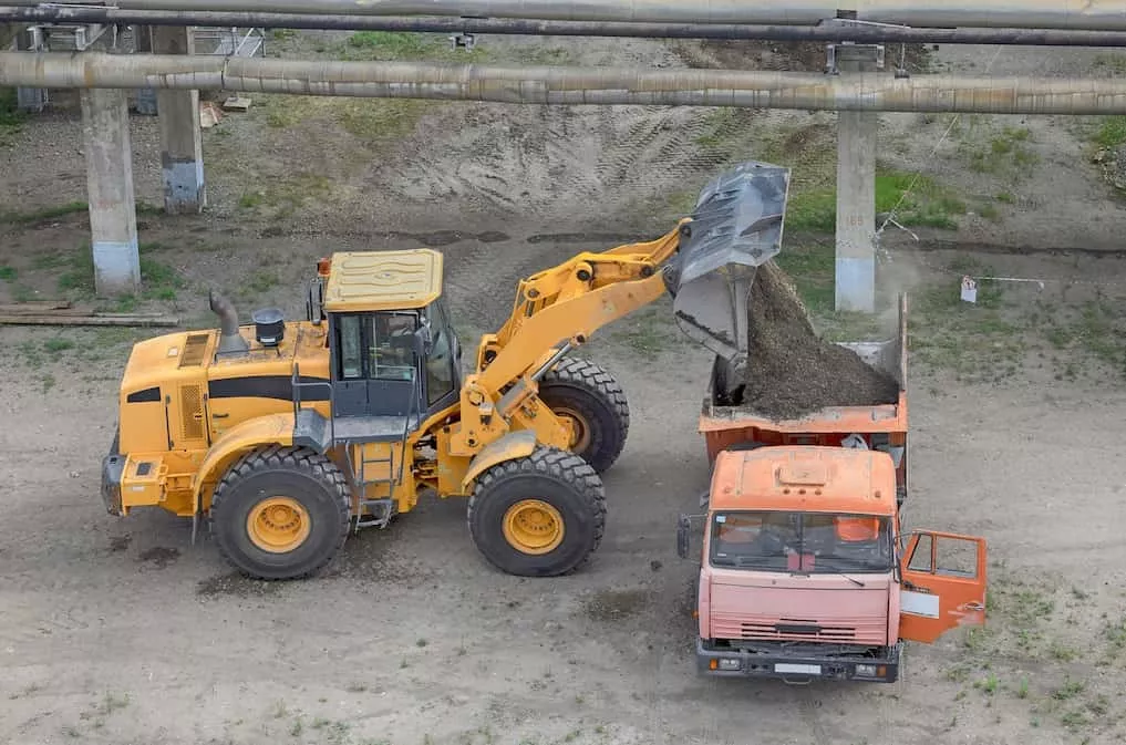 Wheel loader dumping material into a truck during a loading cycle