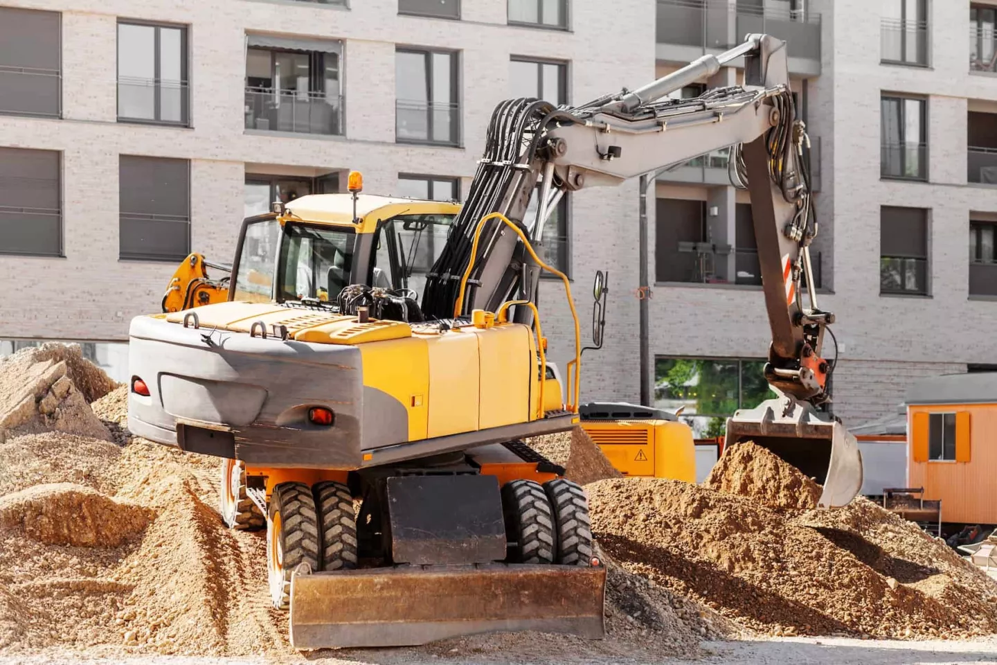 Wheeled excavator performing earthmoving operations at an urban construction site