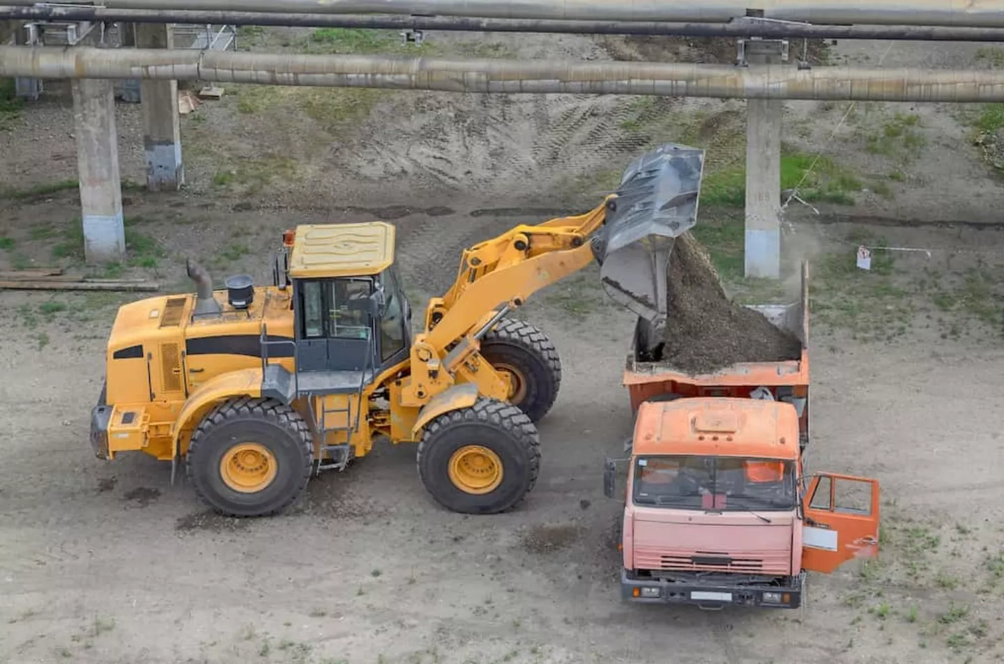 Wheel loader lifting and dumping material into a truck at a construction site